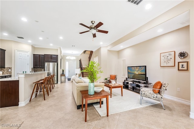 living room with crown molding, light tile patterned floors, and ceiling fan