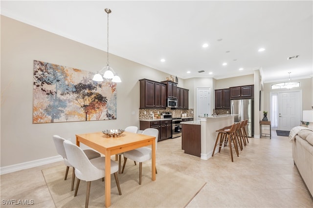 tiled dining area featuring ornamental molding and an inviting chandelier