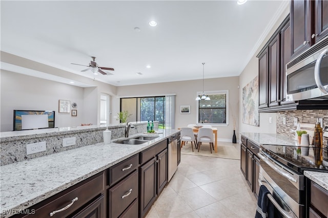 kitchen with appliances with stainless steel finishes, sink, hanging light fixtures, ceiling fan, and light stone counters