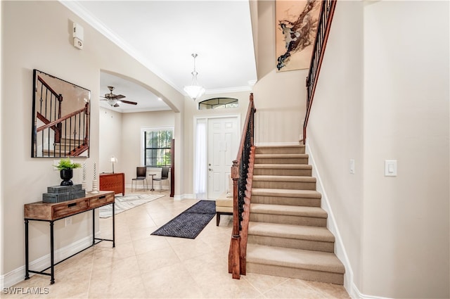 tiled entrance foyer featuring crown molding and ceiling fan