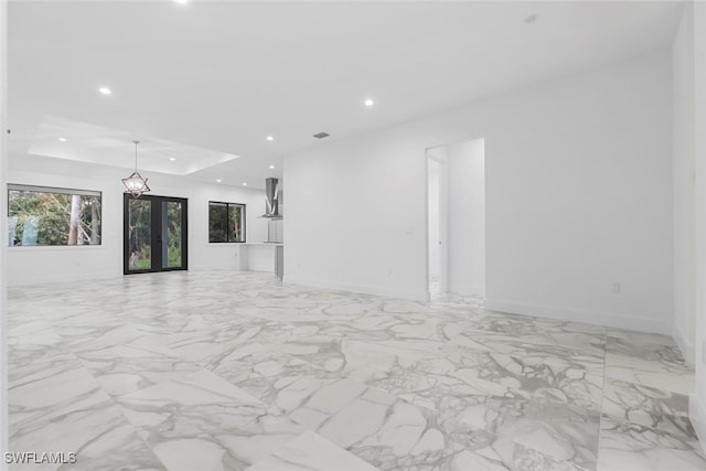 unfurnished living room featuring french doors and a tray ceiling