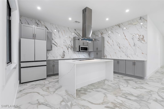 kitchen featuring a kitchen island, island range hood, black electric cooktop, gray cabinetry, and white fridge