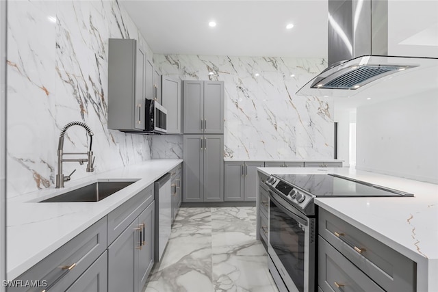 kitchen with light stone countertops, appliances with stainless steel finishes, sink, island range hood, and gray cabinets