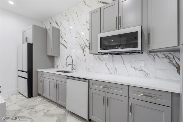 kitchen with white appliances, light stone countertops, sink, gray cabinets, and decorative backsplash