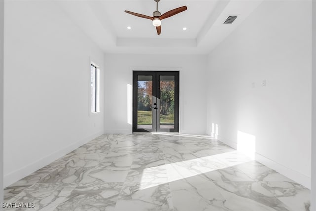 spare room with french doors, a tray ceiling, and ceiling fan