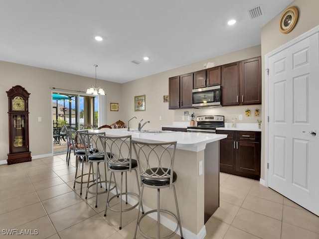 2739 Merida Ln, Cape Coral, FL 33909 - kitchen with a kitchen breakfast bar, a center island with sink, light tile patterned flooring, light countertops, and appliances with stainless steel finishes