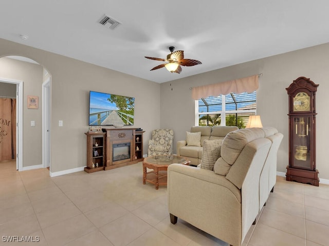 2739 Merida Ln, Cape Coral, FL 33909 - living room with light tile patterned flooring, a glass covered fireplace, ceiling fan, arched walkways, and visible vents