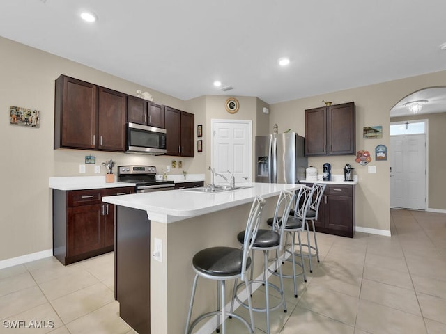 2739 Merida Ln, Cape Coral, FL 33909 - kitchen featuring light countertops, a sink, arched walkways, a kitchen bar, and appliances with stainless steel finishes