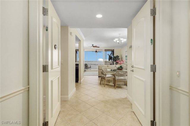 hall featuring crown molding, a notable chandelier, and light tile patterned flooring