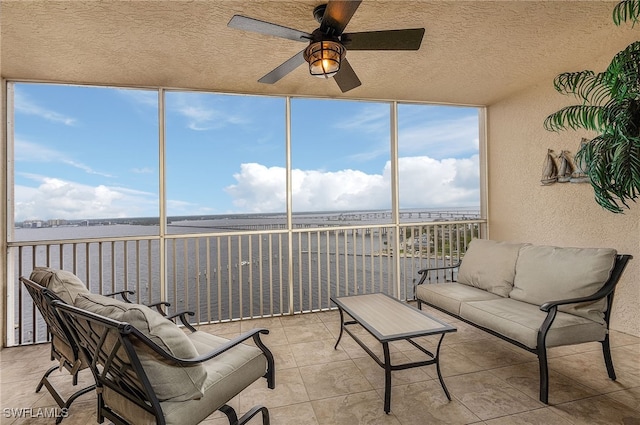 sunroom / solarium with a water view and ceiling fan