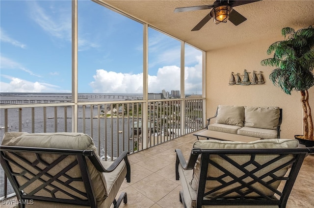 sunroom featuring a water view and ceiling fan