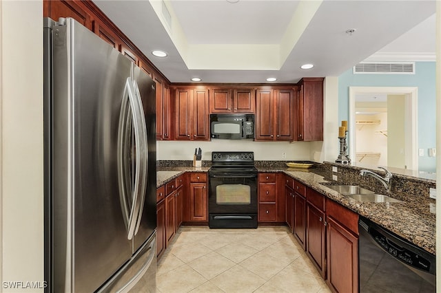 kitchen featuring black appliances, sink, a tray ceiling, dark stone countertops, and light tile patterned floors