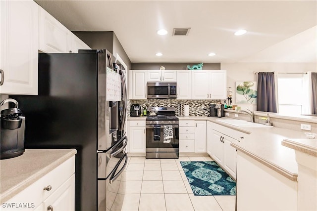 kitchen featuring appliances with stainless steel finishes, backsplash, sink, light tile patterned floors, and white cabinets