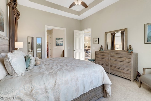 bedroom featuring light carpet, a tray ceiling, and ceiling fan