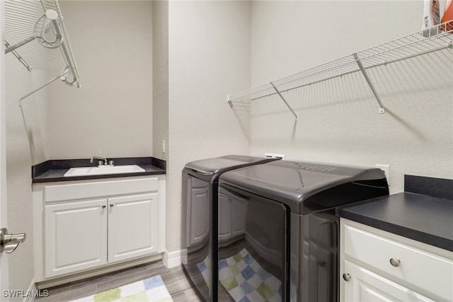 washroom with cabinets, light hardwood / wood-style flooring, sink, and washing machine and clothes dryer