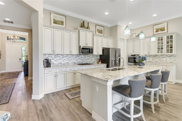 kitchen with a center island with sink, white cabinetry, light stone countertops, light hardwood / wood-style floors, and stainless steel appliances