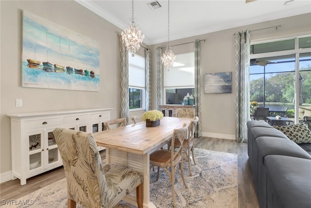 dining room featuring crown molding, an inviting chandelier, plenty of natural light, and hardwood / wood-style floors