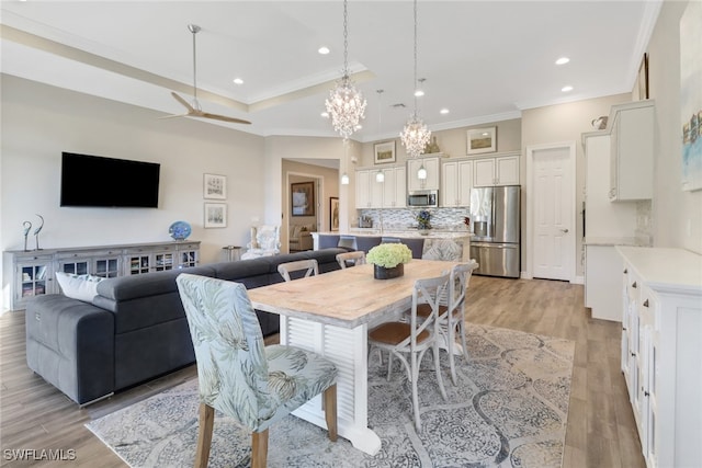 dining room featuring ornamental molding, ceiling fan with notable chandelier, and light wood-type flooring