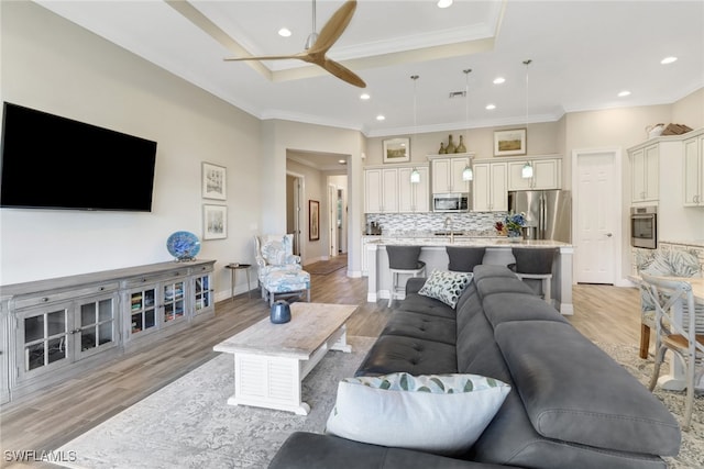 living room featuring ornamental molding, sink, light wood-type flooring, and ceiling fan