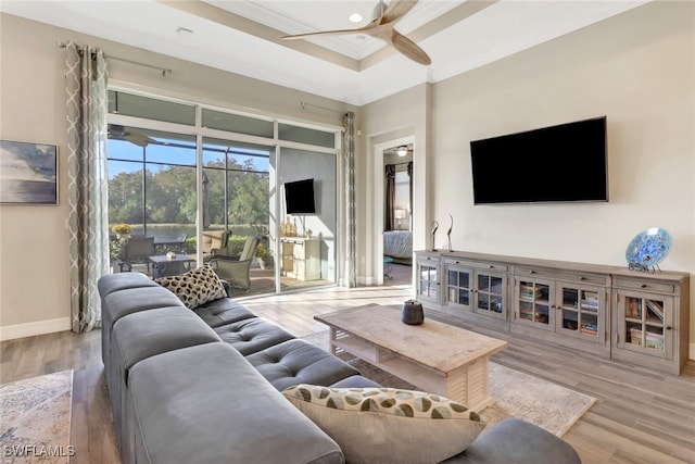 living room featuring ornamental molding, hardwood / wood-style floors, a raised ceiling, and ceiling fan