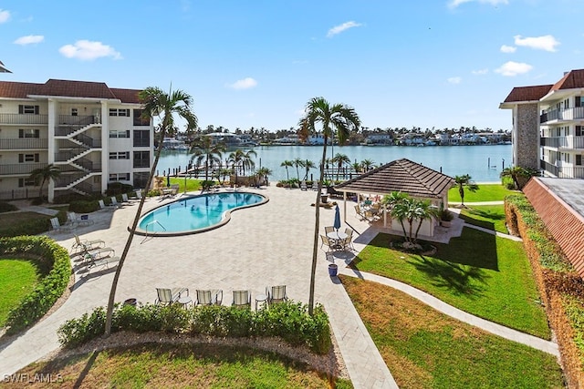 view of pool featuring a patio area, a lawn, and a water view