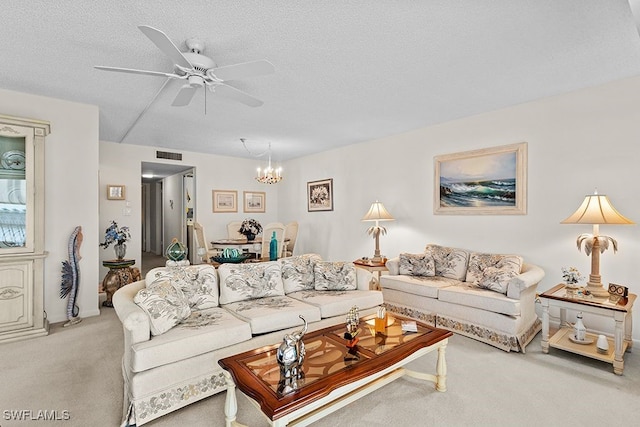 carpeted living room featuring a textured ceiling and ceiling fan with notable chandelier