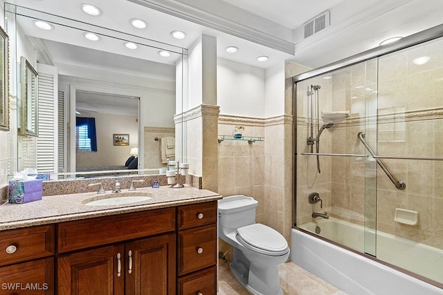 full bathroom with toilet, tile walls, bath / shower combo with glass door, vanity, and tile patterned flooring