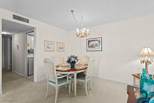 dining room with washer / dryer, light carpet, a textured ceiling, and a chandelier