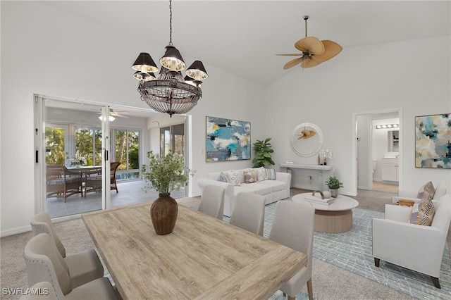 dining space featuring ceiling fan with notable chandelier, high vaulted ceiling, and light colored carpet