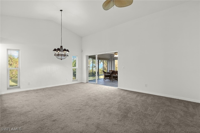 carpeted empty room featuring high vaulted ceiling, a healthy amount of sunlight, and ceiling fan with notable chandelier