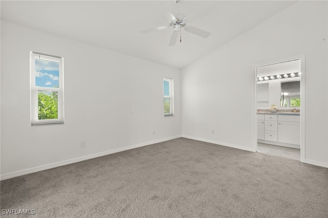 unfurnished room featuring a healthy amount of sunlight, vaulted ceiling, and light colored carpet