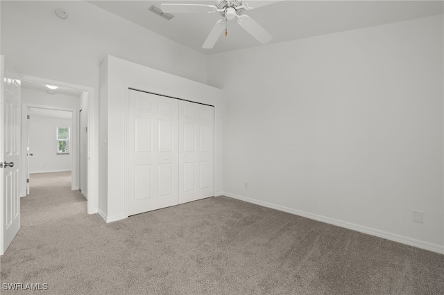 unfurnished bedroom with light colored carpet, a closet, and ceiling fan