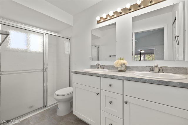 bathroom with toilet, a shower with shower door, vanity, and tile patterned floors