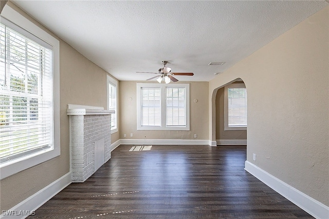 unfurnished living room featuring a textured ceiling, a wealth of natural light, and dark hardwood / wood-style floors