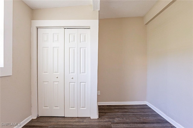 unfurnished bedroom with a closet, a textured ceiling, and dark hardwood / wood-style floors