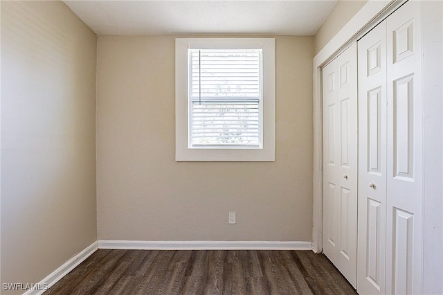 unfurnished bedroom with dark wood-type flooring, a textured ceiling, and a closet