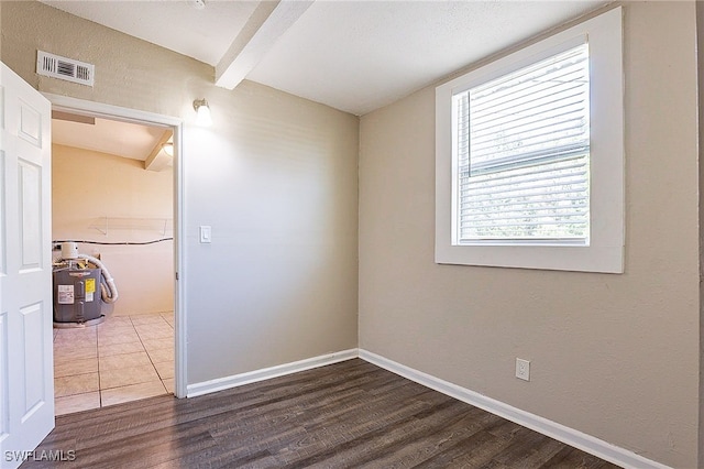 spare room with beam ceiling and hardwood / wood-style floors