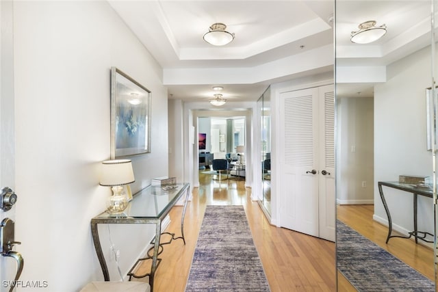 hallway featuring light hardwood / wood-style floors and a raised ceiling