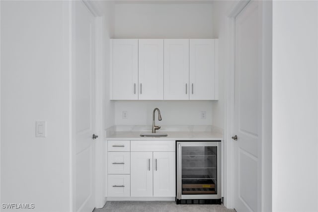 bar with wine cooler, white cabinets, and sink