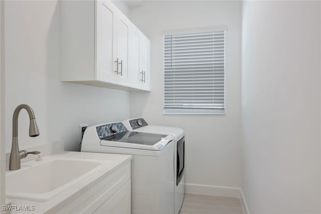 laundry room with a sink, washing machine and clothes dryer, cabinet space, and baseboards