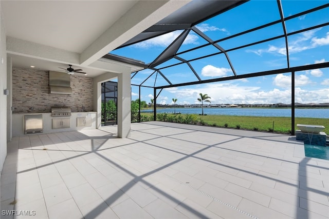 view of patio / terrace featuring glass enclosure, ceiling fan, a water view, a grill, and exterior kitchen