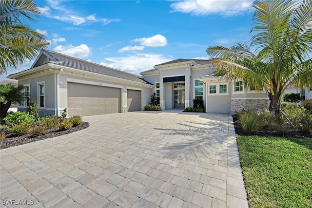 view of front of house featuring an attached garage, a tile roof, stone siding, decorative driveway, and stucco siding