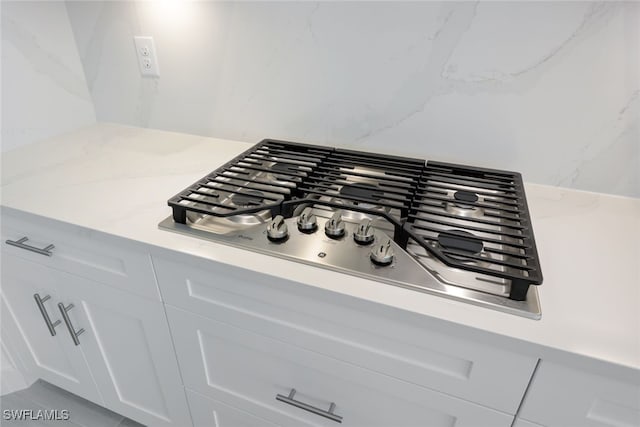 room details with light stone countertops, stainless steel gas stovetop, and white cabinetry