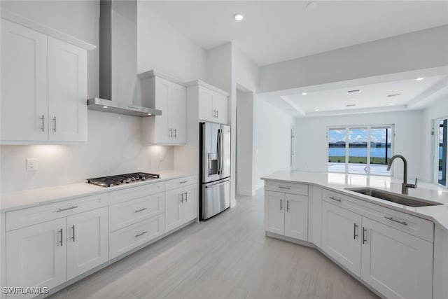 kitchen featuring light countertops, appliances with stainless steel finishes, wall chimney exhaust hood, and a sink