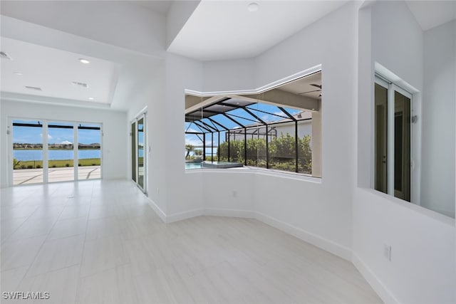 spare room with a sunroom, a water view, visible vents, and baseboards