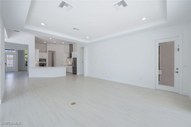 unfurnished living room with a raised ceiling