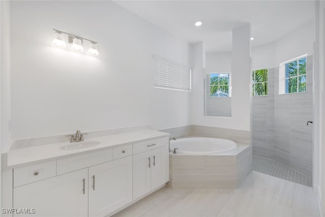 bathroom with a garden tub, recessed lighting, a walk in shower, and vanity