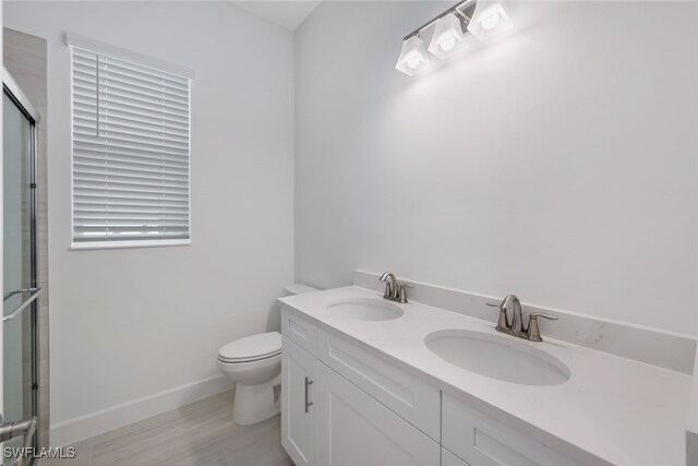 bathroom with vanity, wood-type flooring, toilet, and an enclosed shower