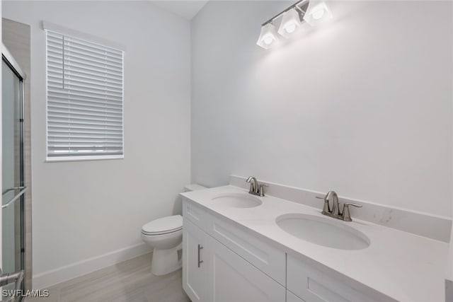 bathroom featuring double vanity, an enclosed shower, a sink, and toilet