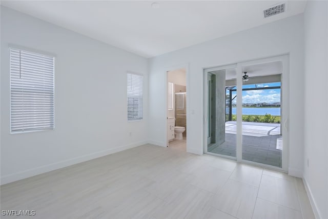 spare room featuring a ceiling fan, a water view, visible vents, and baseboards